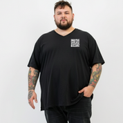 Front view of a man wearing black Inhale Good Shit Exhale Bullshit v neck tee, relaxed fit, bold wavy white typography, plus size Australian streetwear by Bae Bands