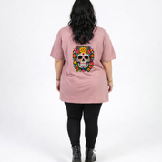Person wearing a pink t-shirt with a colorful skull design on the back, standing against a white background.