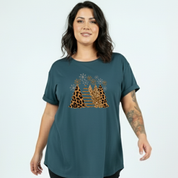 Woman wearing a teal t-shirt with a graphic design on a light blue background