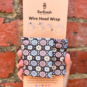 Bae Bands wire head wrap with floral pattern held against a brick wall.