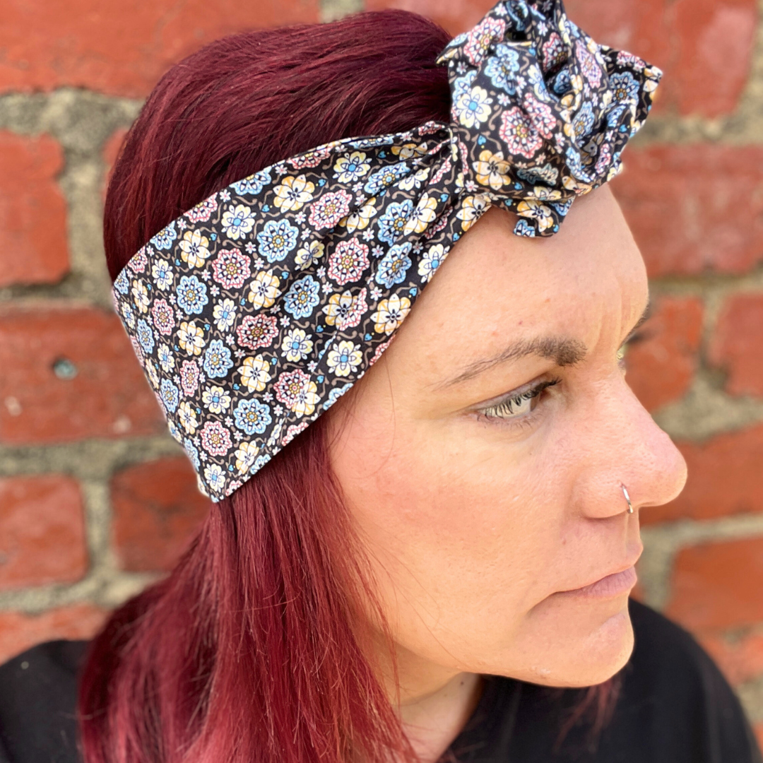 Woman wearing a floral headband against a brick wall