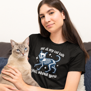Woman wearing a black t-shirt with a cat skeleton design and text, sitting on a couch with a cat.