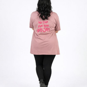 Person wearing a pink t-shirt with text on the back, standing against a white background