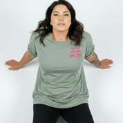 Woman wearing a green t-shirt with pink text on a white background