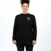 Woman wearing black long sleeve graphic tee with large intricate pink and teal mandala back print, plus size Australian streetwear by Bae Bands