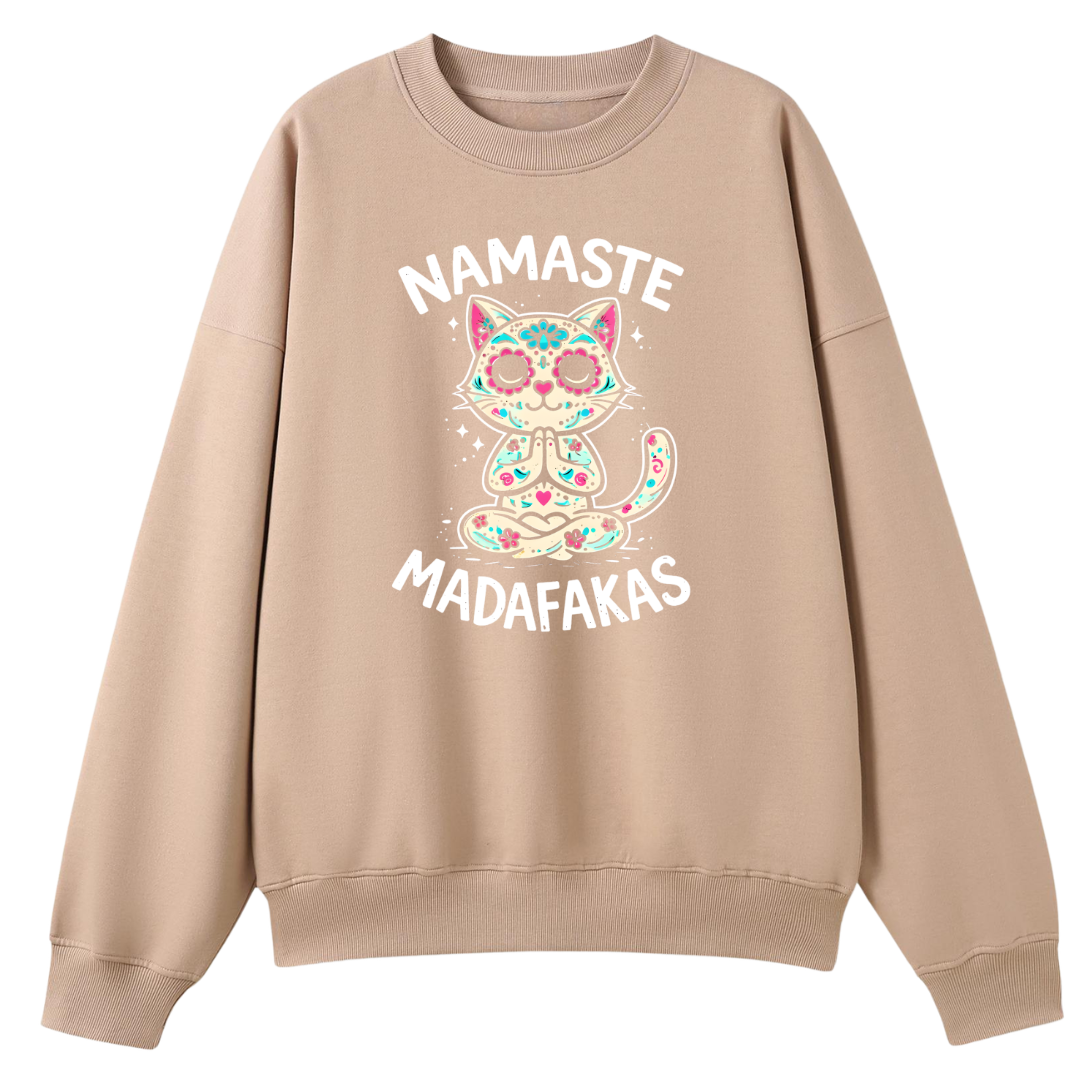 A beige crewneck sweatshirt featuring a colorful graphic of a cat with sugar skull makeup and the text 'NAMASTE MADAFAKAS' in white, displayed on a solid white background.