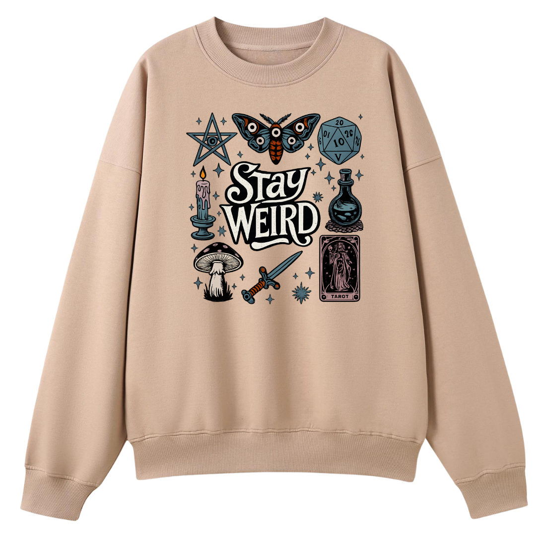 A beige crewneck sweatshirt featuring a gothic-themed graphic print on the front with the words 'Stay Weird' surrounded by illustrations of a butterfly, a pentagram, a d20 die, a potion bottle, a mushroom, a dagger, and tarot cards.