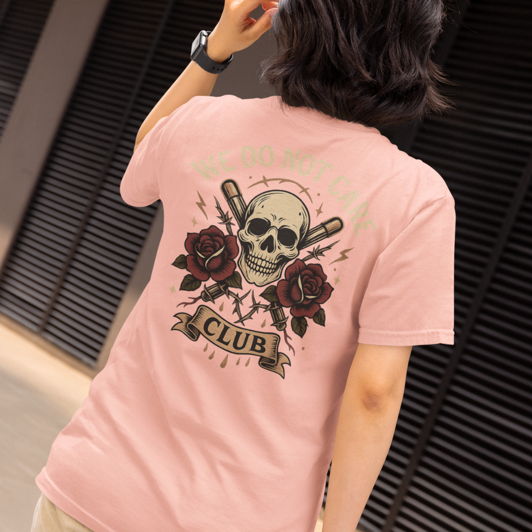 Plus-size Pink streetwear tee with “We Do Not Care Club” skull and cross-bat graphic, red roses and barbed wire detail – limited release