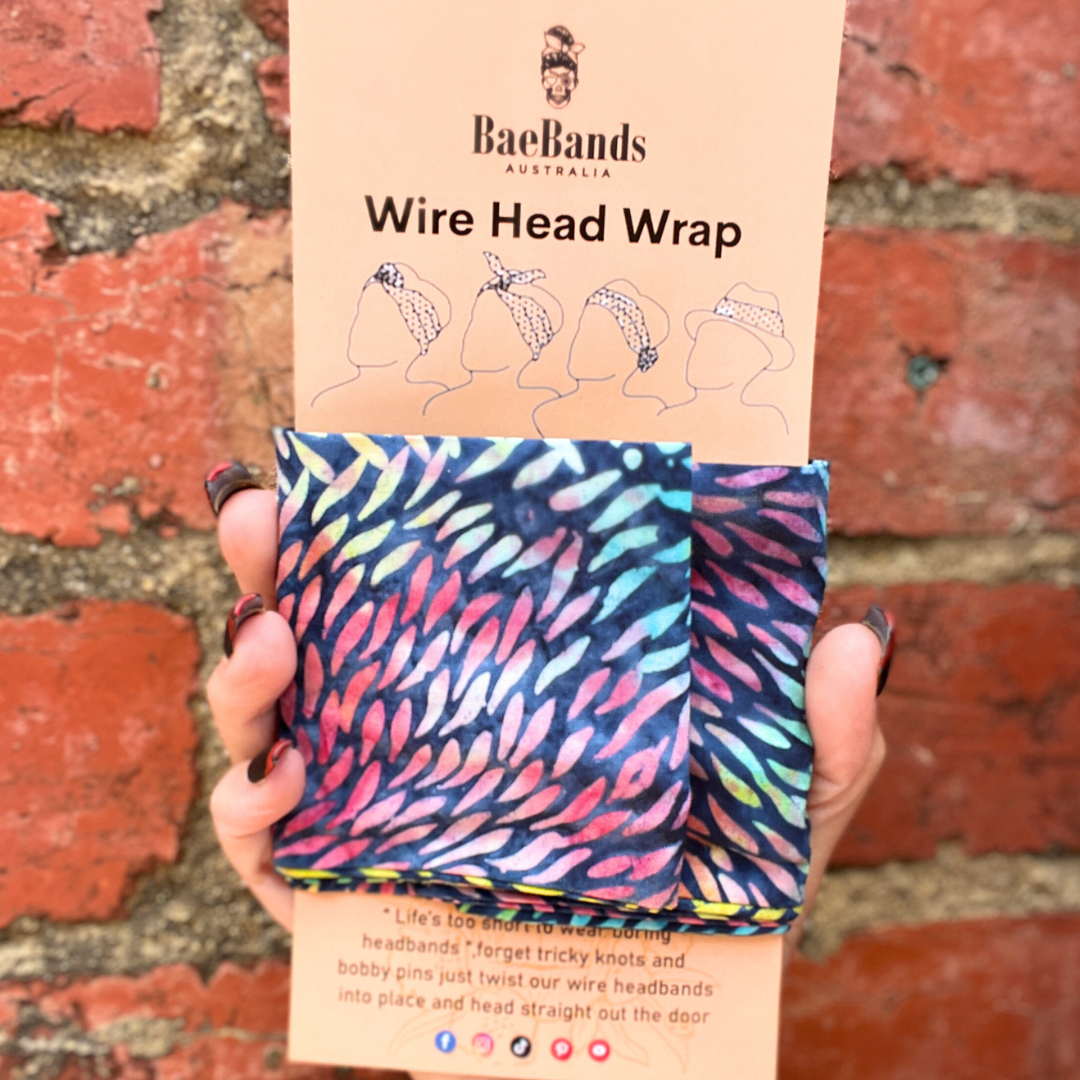 Wire head wrap with colorful pattern held against a brick wall, featuring Bae Bands packaging.