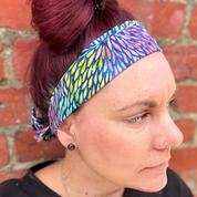 Person wearing a colorful headband with a brick wall background
