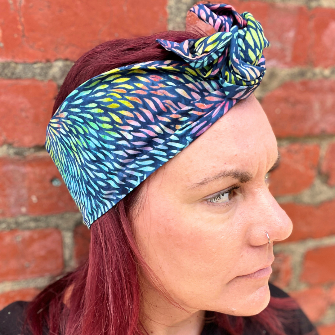 Person wearing a colorful headscarf against a brick wall
