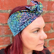 Person wearing a colorful headscarf against a brick wall