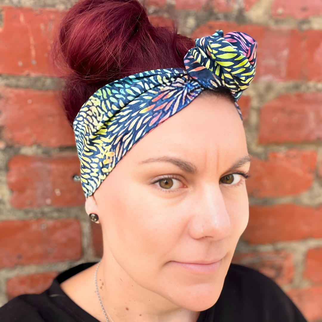 Woman wearing a colorful headscarf against a brick wall