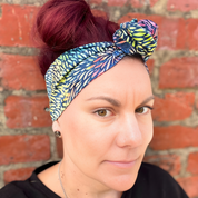 Woman wearing a colorful headscarf against a brick wall
