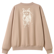 A beige crewneck sweatshirt shown from the back, featuring a distressed white graphic of a raccoon on the upper back.