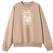 A beige crewneck sweatshirt featuring a white distressed raccoon graphic on the front, displayed against a solid white background.