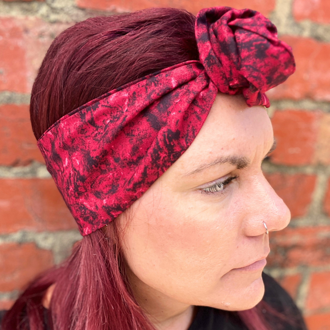 Person wearing a red patterned headband against a brick wall