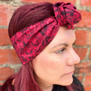Person wearing a red patterned headband against a brick wall