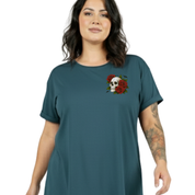 A woman wearing a teal short-sleeve t-shirt with a small chest graphic of a skull and red roses, set against a plain white background.