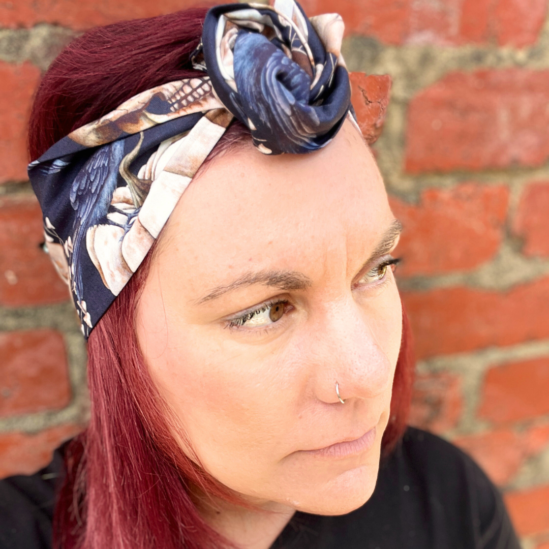 Woman with a floral headscarf against a brick wall