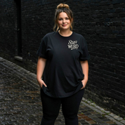 Front view of woman wearing black Stay Weird oversized tee, relaxed drop shoulder fit, plus size Australian streetwear by Bae Bands