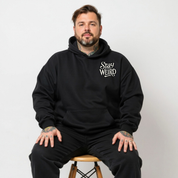Front view of a man wearing black Stay Weird hoodie, relaxed fit, plus size Australian streetwear by Bae Bands