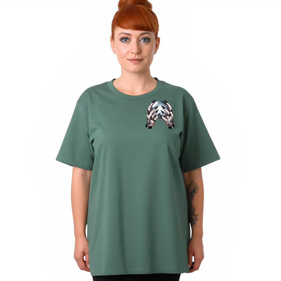 A woman with red hair in a bun wearing a sage green t-shirt with a black and white geometric patterned graphic on the left chest, set against a plain white background.