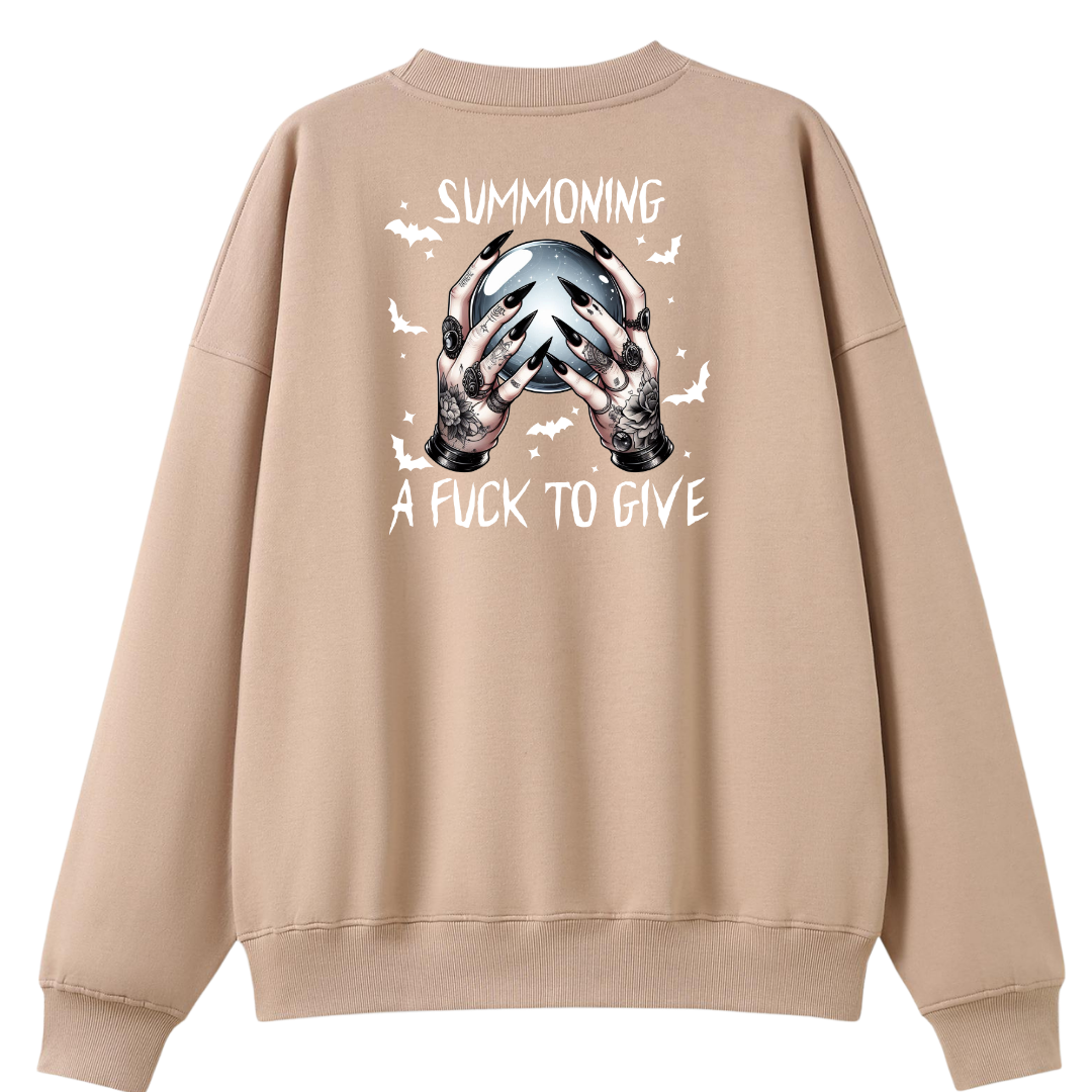 A beige crewneck sweatshirt shown from the back, featuring a graphic of tattooed hands holding a skull with the text 'SUMMONING A FUCK TO GIVE' and small bat silhouettes.