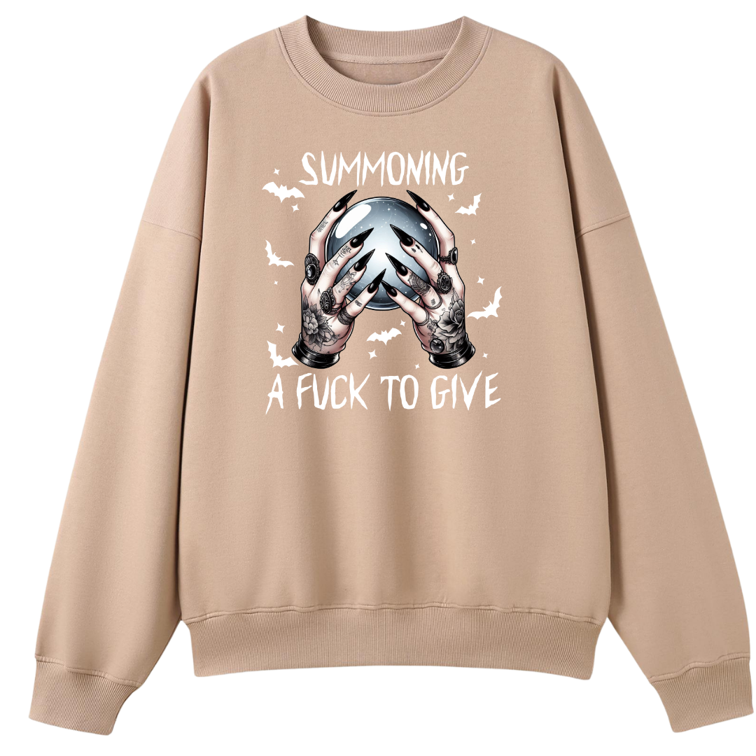 A beige crewneck sweatshirt featuring a graphic of tattooed hands holding a skull with the text 'SUMMONING A FUCK TO GIVE' and small white bats.