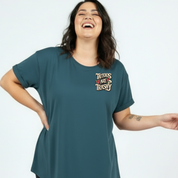 Woman wearing a teal t-shirt with 'Tattoos Are Trashy' text on a white background