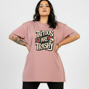 Person wearing a pink t-shirt with 'Tattoos Are Trashy' text and graphics on a white background