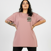 Person wearing a pink t-shirt with 'Tattoos Are Trashy' text on a plain background