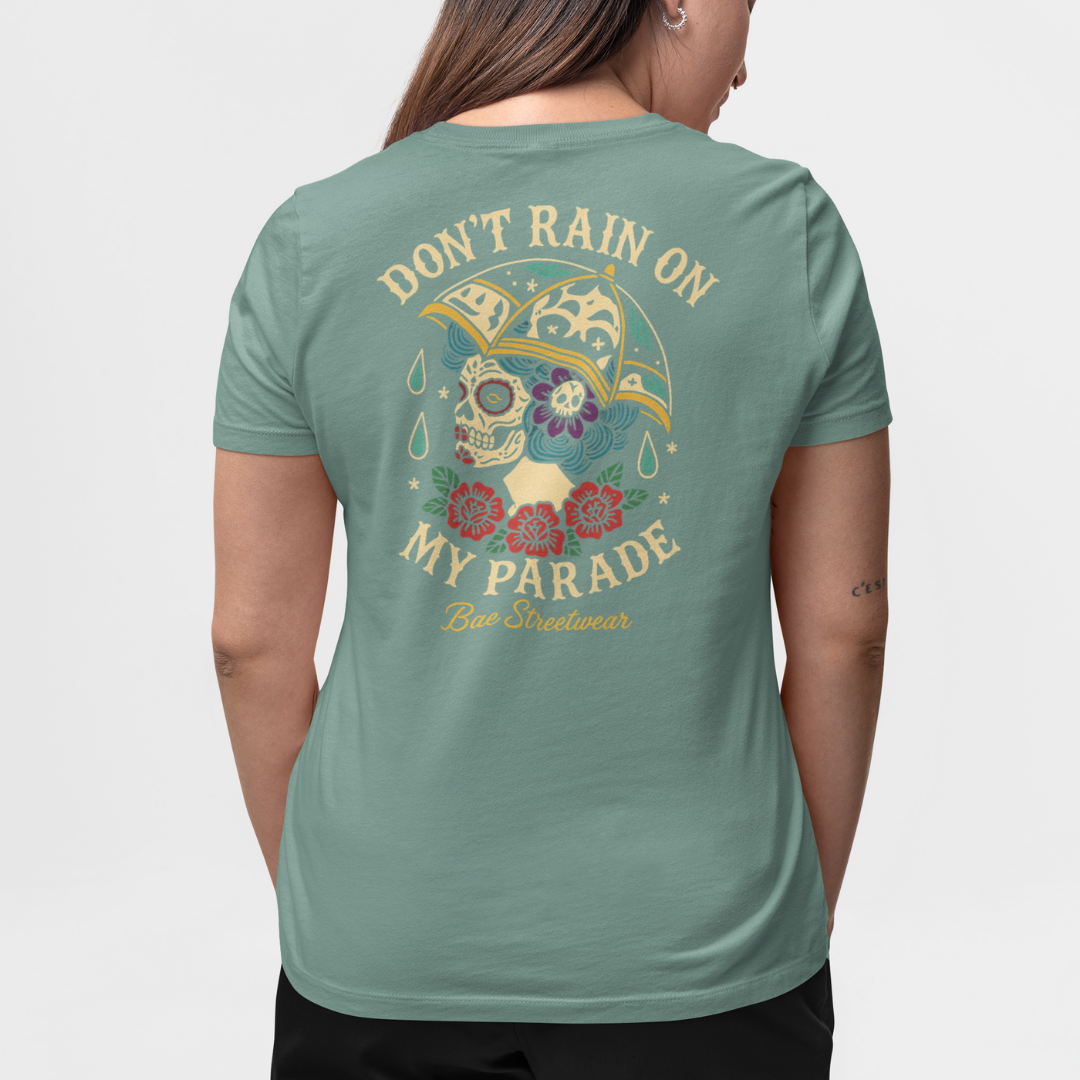 Teal graphic tee featuring Day of the Dead skull with umbrella, teal raindrops, and bold ‘Don’t Rain On My Parade’ slogan – limited edition plus-size streetwear
