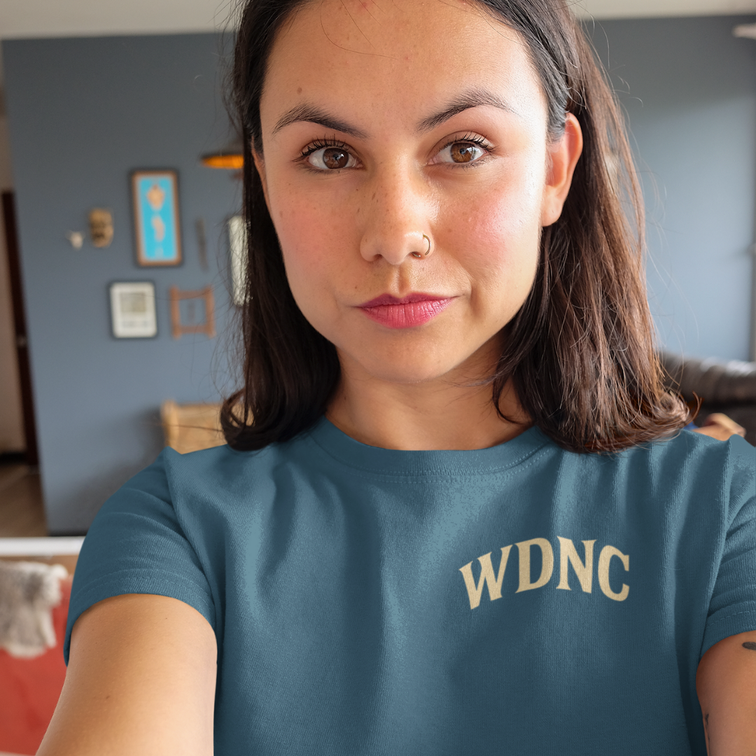 Unisex Teal oversized tee with bold “We Do Not Care Club” lettering, detailed skull and crossed bat design framed by red roses