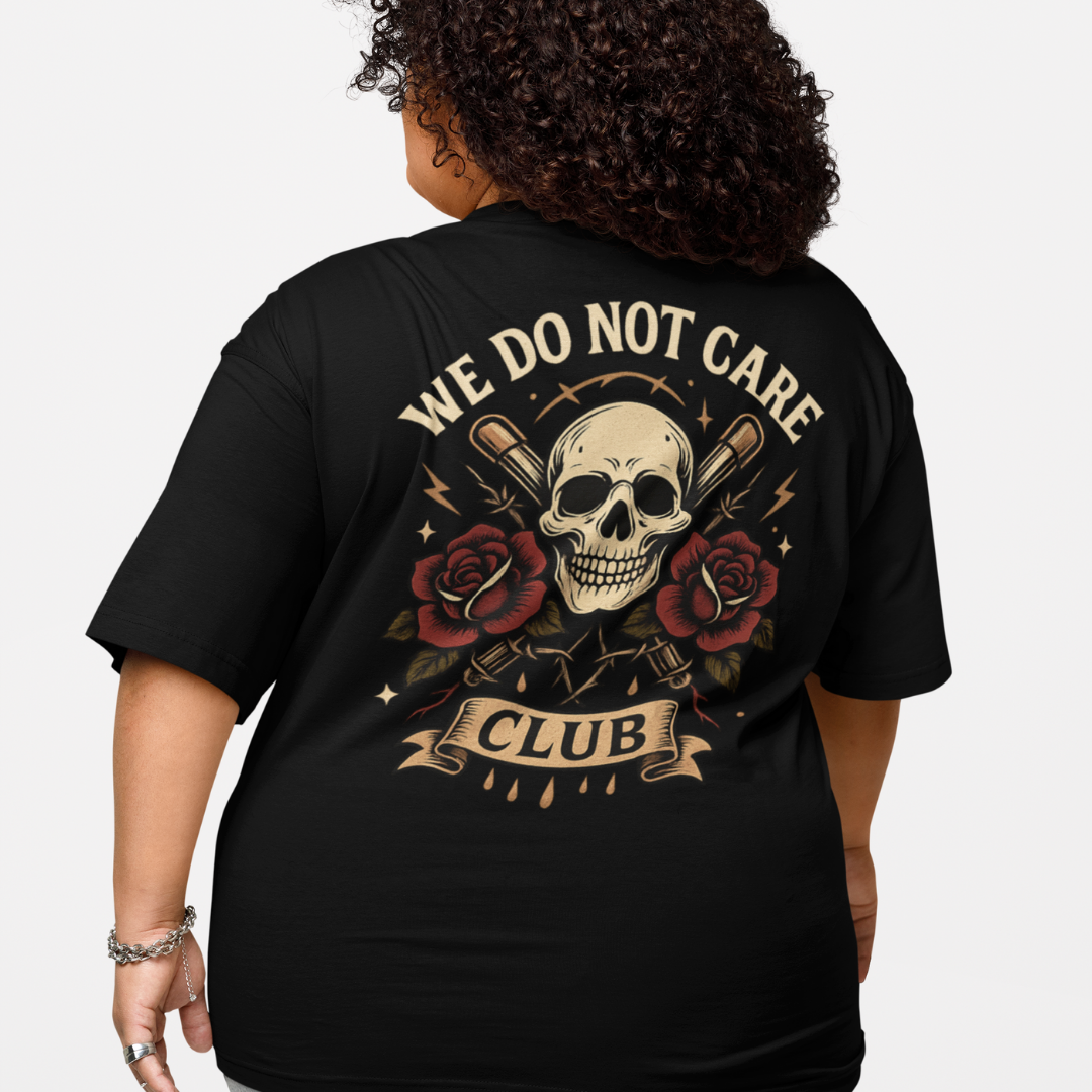 Black plus-size oversized tee with “We Do Not Care Club” curved text, skull centerpiece, crossed baseball bats, barbed-wire and red rose accents by Bae Streetwear