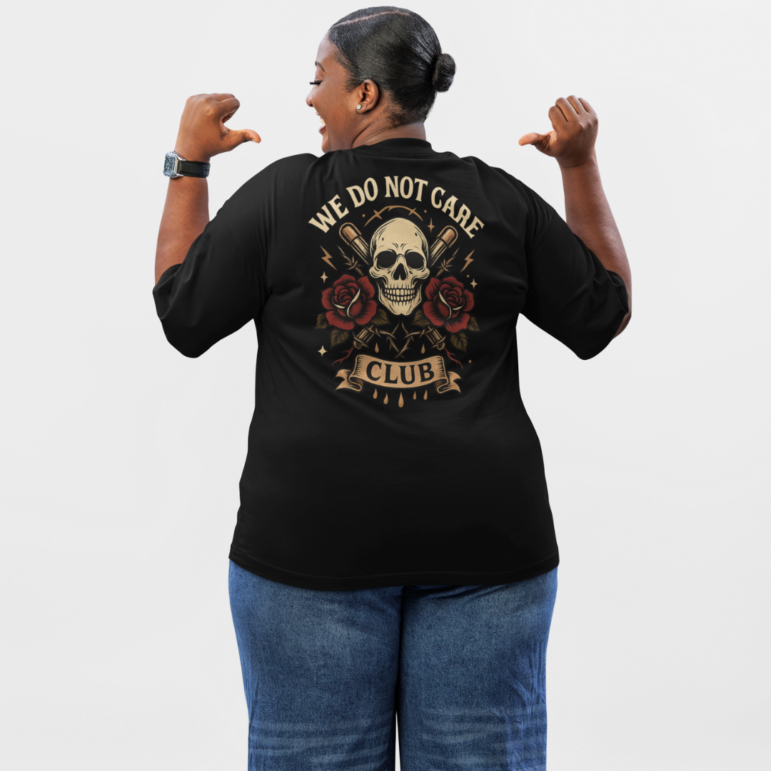 Limited-edition plus-size streetwear tee in black displaying “We Do Not Care Club” text, skull motif, crossed bats and floral rose embellishments