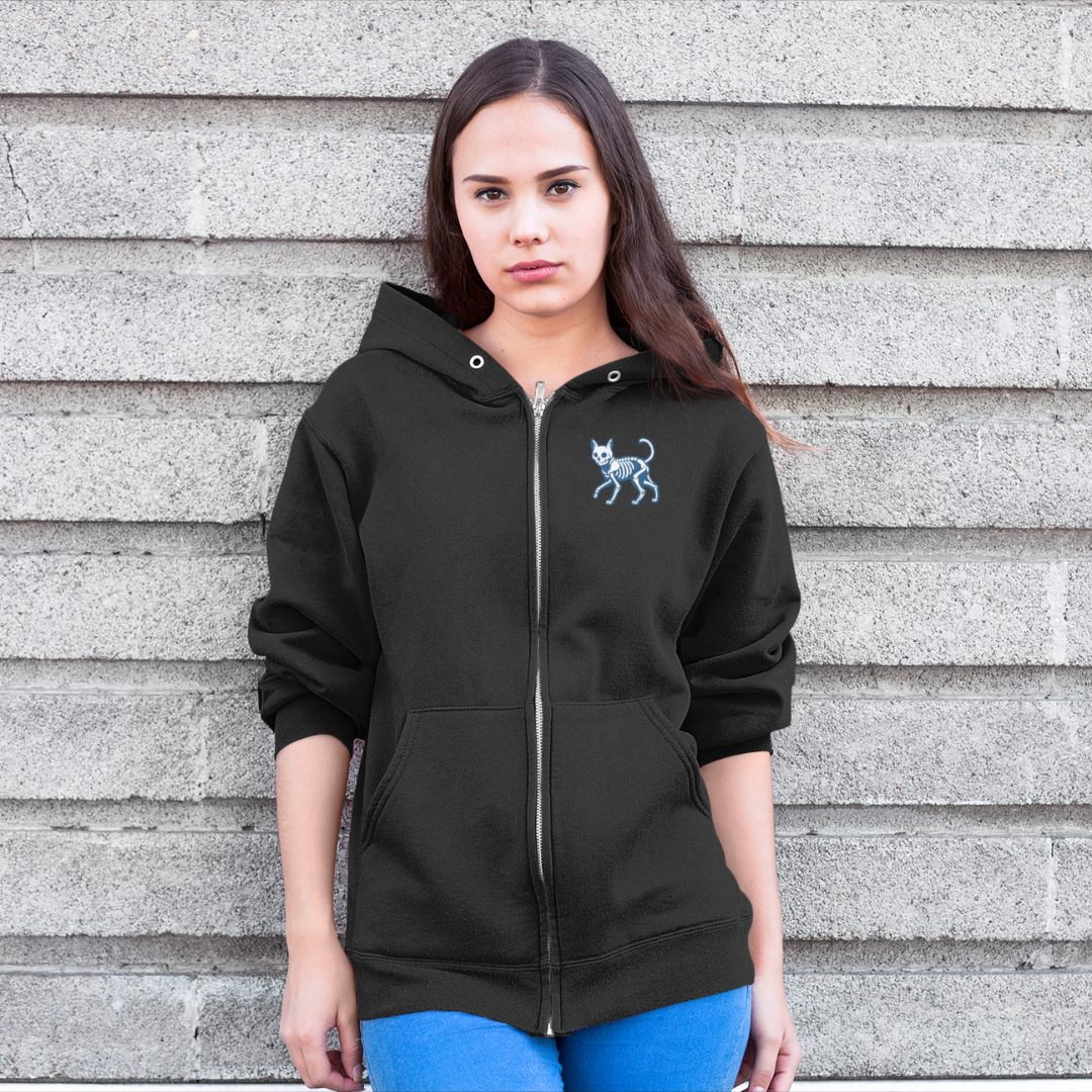 Person wearing a black hoodie with a small design on a gray wall