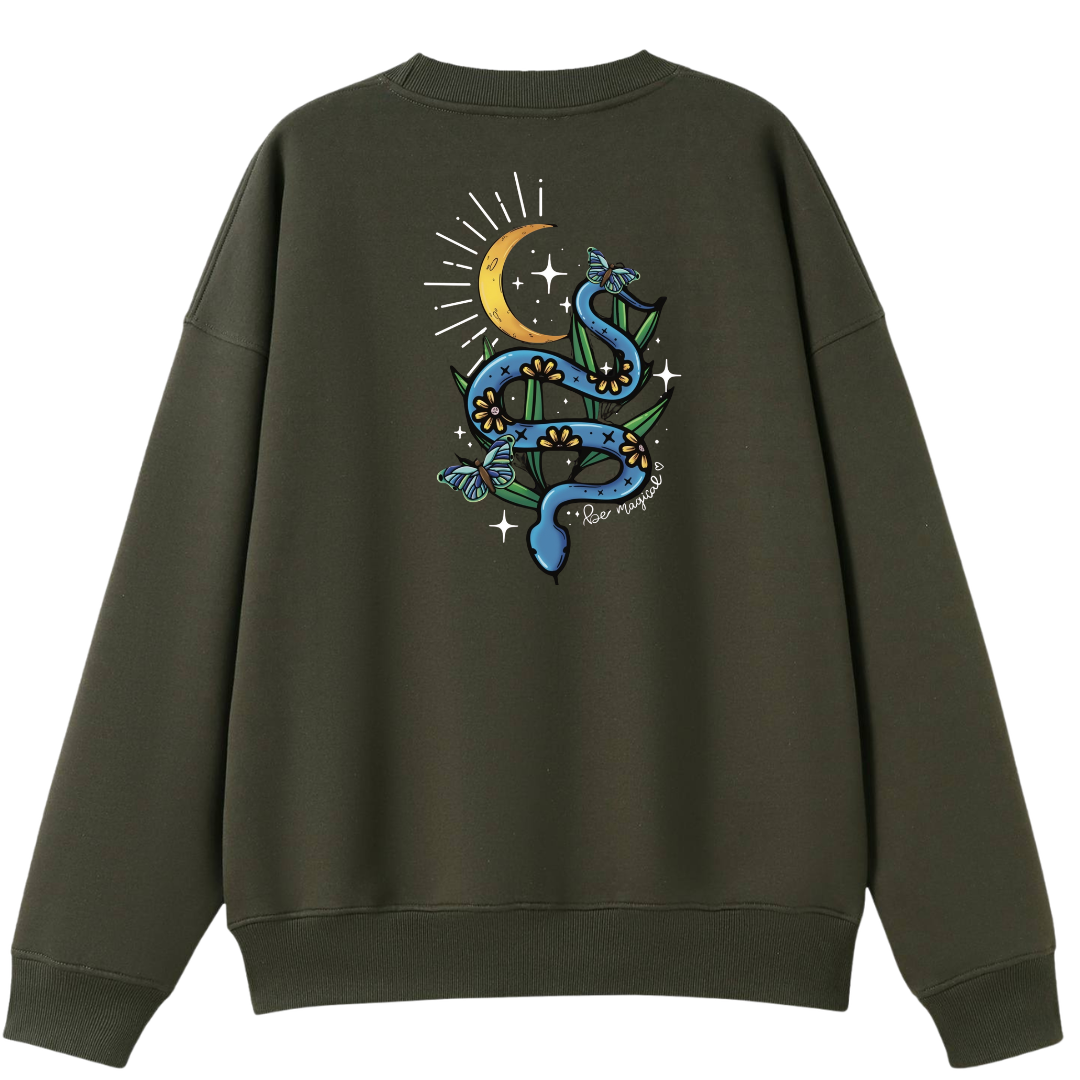 An army green oversized crew neck shown from the back, with the Be Magic snake graphic printed large across the back, a blue floral snake with butterflies under a crescent moon.