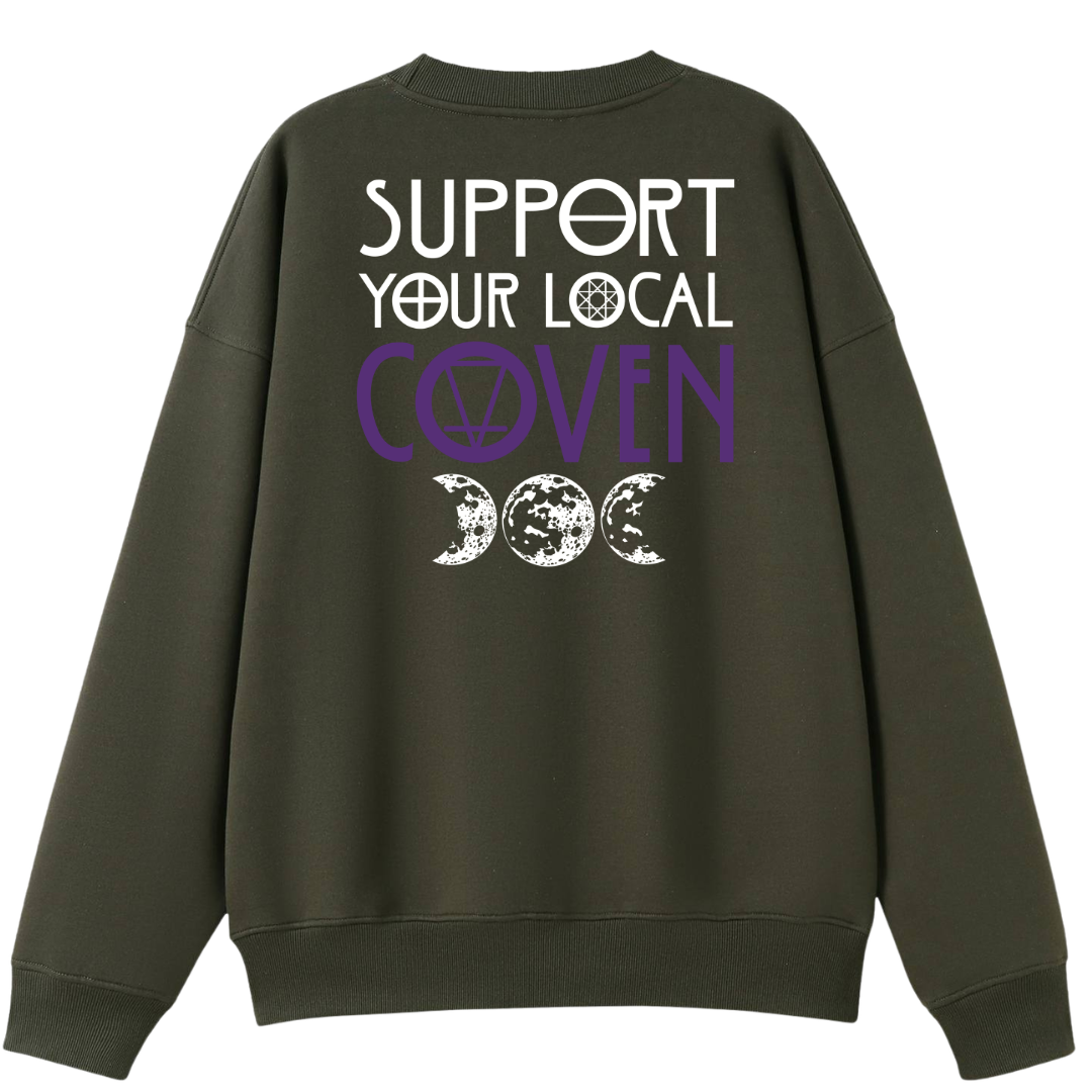 An army green oversized crew neck shown from the back, with the Support Your Local Coven graphic printed large across the back, purple lettering above a triple moon.