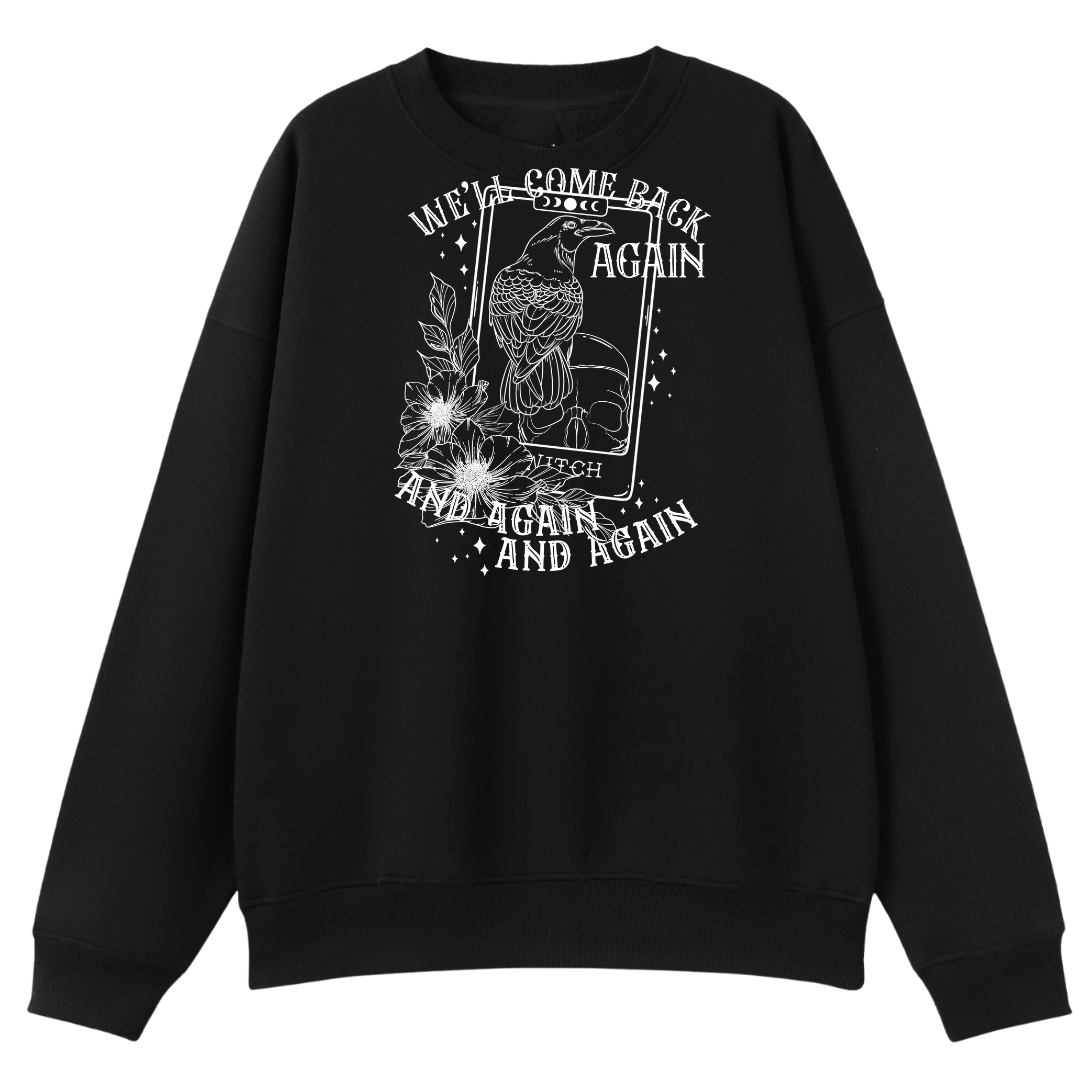 A black oversized crew neck with the We'll Come Back Again graphic printed large on the front, a crow on a tarot card framed by flowers.
