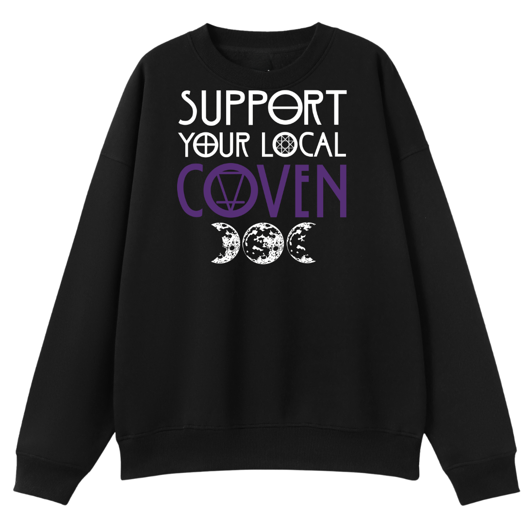 A black oversized crew neck with the Support Your Local Coven graphic printed large on the front, purple lettering above a triple moon.