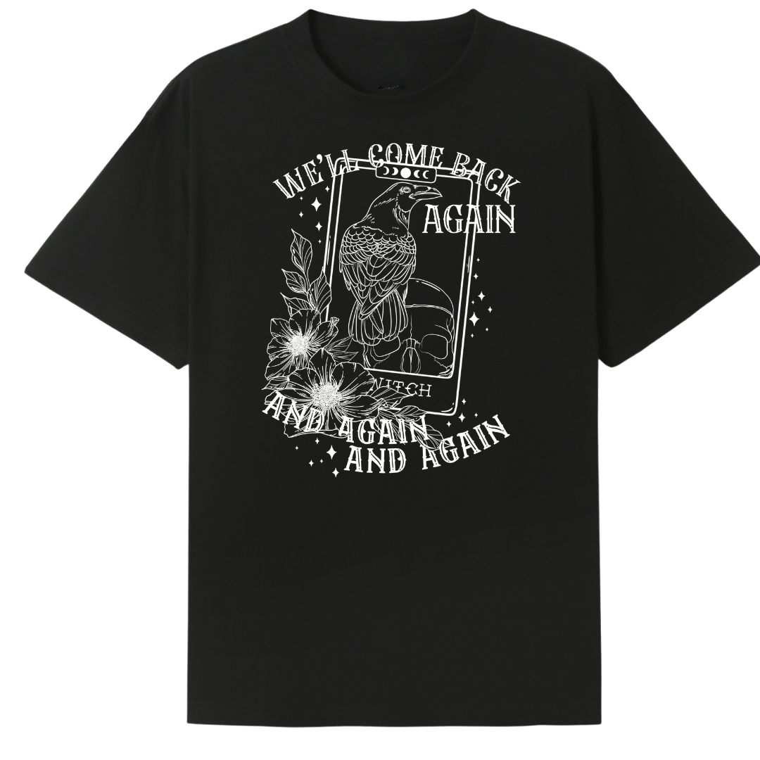 A black oversized tee with the We'll Come Back Again graphic printed large on the front, a crow on a tarot card framed by flowers.