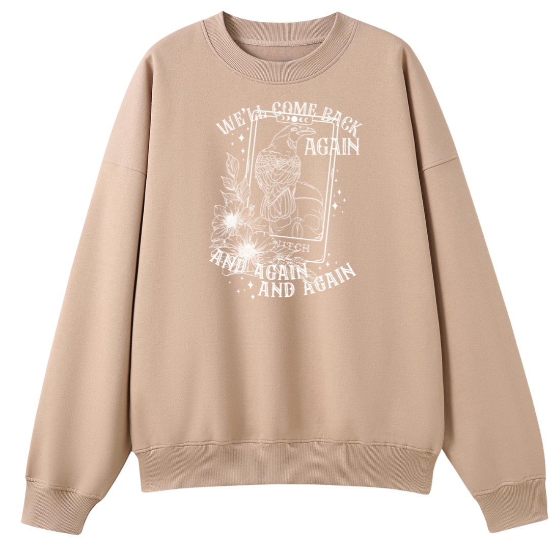 A peach oversized crew neck with the We'll Come Back Again graphic printed large on the front, a crow on a tarot card framed by flowers.
