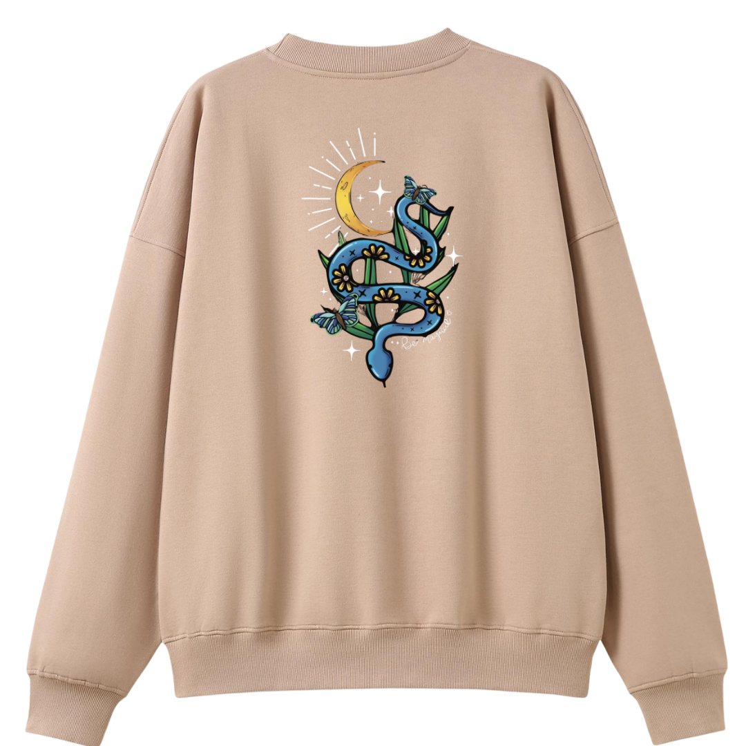 A peach oversized crew neck shown from the back, with the Be Magic snake graphic printed large across the back, a blue floral snake with butterflies under a crescent moon.