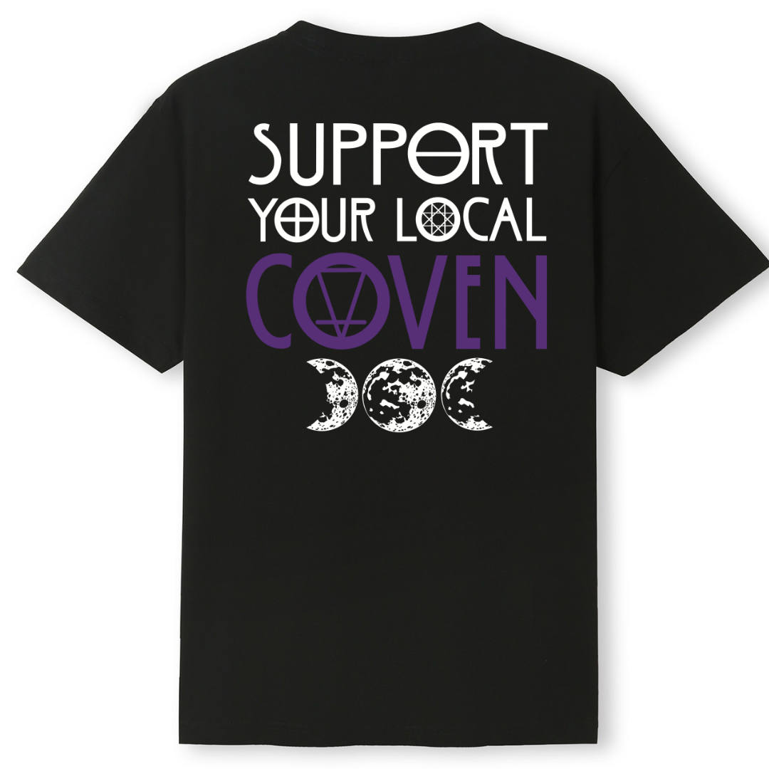 A black oversized tee shown from the back, with the Support Your Local Coven graphic printed large across the back, purple lettering above a triple moon.