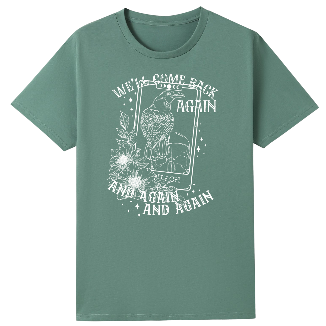 A slate green oversized tee with the We'll Come Back Again graphic printed large on the front, a crow on a tarot card framed by flowers.
