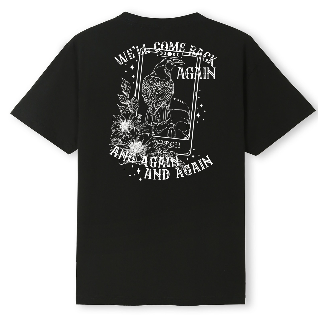 A black oversized tee shown from the back, with the We'll Come Back Again graphic printed large across the back, a crow on a tarot card framed by flowers.
