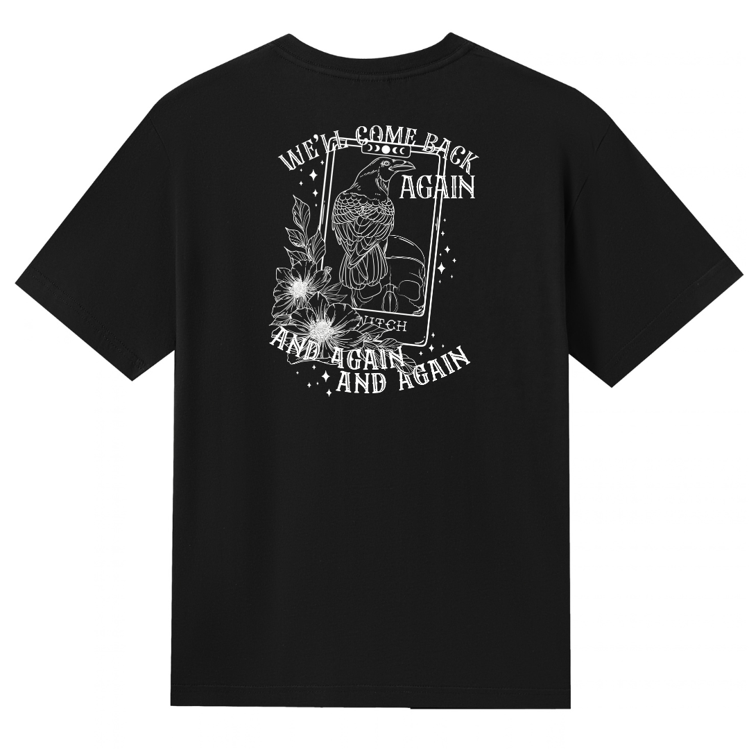 A black V neck oversized tee shown from the back, with the We'll Come Back Again graphic printed large across the back, a crow on a tarot card framed by flowers.