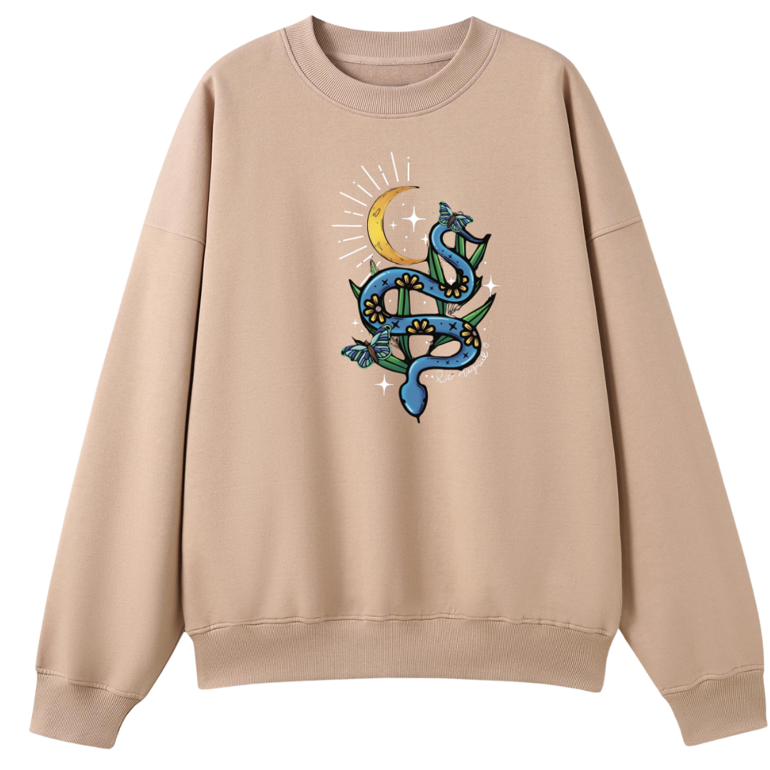 A peach oversized crew neck with the Be Magic snake graphic printed large on the front, a blue floral snake with butterflies under a crescent moon.