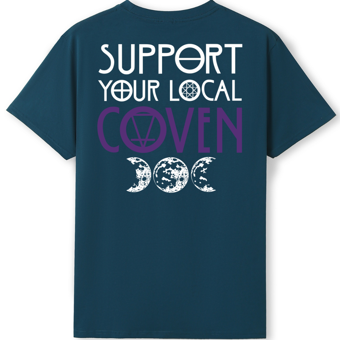 A teal oversized tee shown from the back, with the Support Your Local Coven graphic printed large across the back, purple lettering above a triple moon.